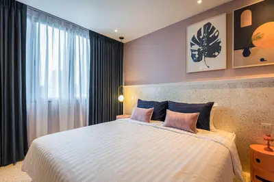 a bedroom with a large bed with two pink pillows at PETRA Designer Apartment Sukhumvit, Nana BTS in Bangkok