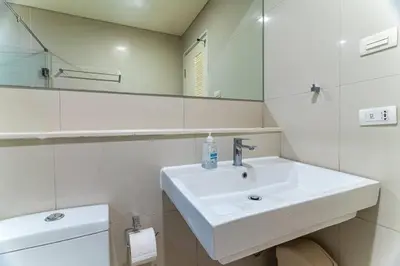 a white bathroom with a sink and a mirror at Thonglor area 1 Bedroom FastWiFi Sauna Big Swimming Pool 43 in Bangkok