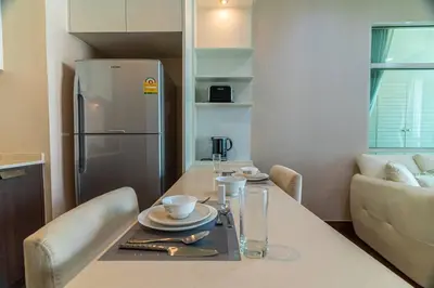 a kitchen with a dining table with a refrigerator at Thonglor area 1 Bedroom FastWiFi Sauna Big Swimming Pool 43 in Bangkok