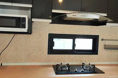 a kitchen with a stove and a microwave at Baan Salaya in Salaya