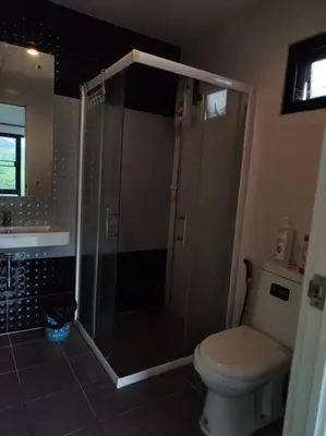 a bathroom with a shower and a toilet and a sink at Baan Salaya in Salaya