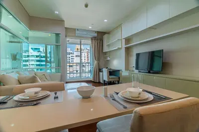 a living room with a table and a tv at Thonglor area 1 Bedroom FastWiFi Sauna Big Swimming Pool 38 in Bangkok