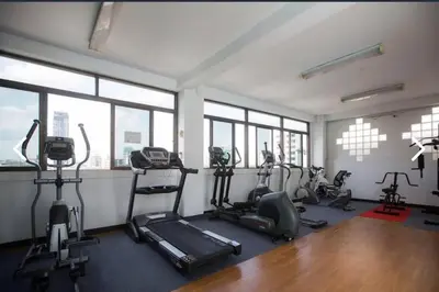a gym with treadmills and ellipticals in a room with windows at Apartment studio at platinum in Bangkok