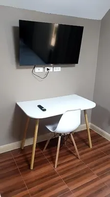 a white table with a chair and a television on a wall at 93 House in Ban Zong Katiam