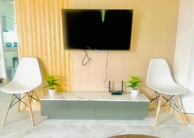 a tv hanging on a wall with two white chairs at 93 House in Ban Zong Katiam