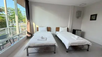 two beds in a room with a large window at Woodview Resort in Samut Prakan