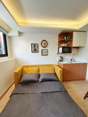 a yellow couch in a room with a kitchen at Brix26 in Bangkok