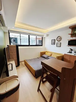 a room with a bed and a desk and a table at Brix26 in Bangkok