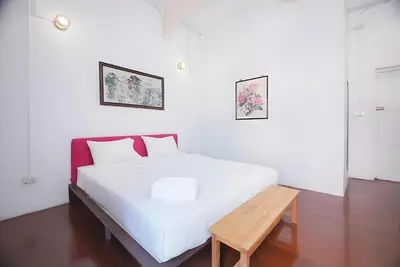 a white bed with a wooden bench in a room at XX Mitr Inn Yaowarat - China Town in Bangkok