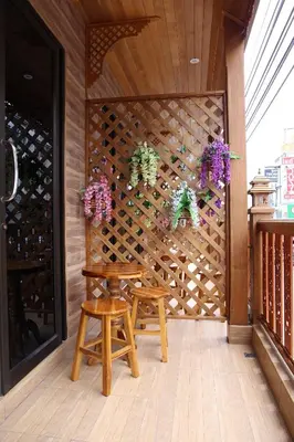 a room with two stools and a wooden wall with flowers at Tanee Place in Bangkok