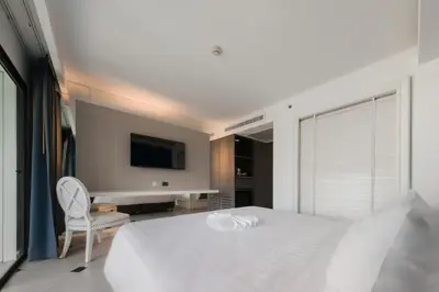 a white bedroom with a white bed and a desk at Skye Hotel Bangkok in Bangkok