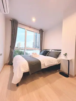 a bedroom with a large bed and a large window at Komfy Quarters in Sathani Bang Khen