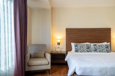 a hotel room with a bed and a chair at Journeyhub Sukhumvit 26, Bangkok - Formerly St James Hotel in Bangkok