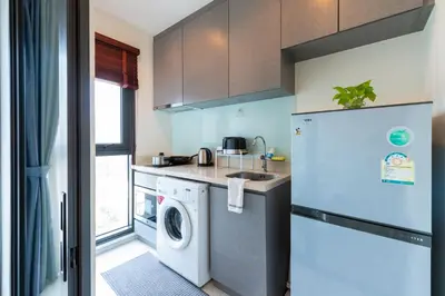 a kitchen with a washing machine and a refrigerator at Luxurious Apartment with Train Access in Bangkok