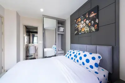 a bedroom with a large white bed and a mirror at Luxurious Apartment with Train Access in Bangkok