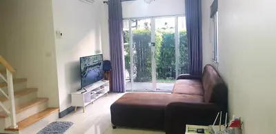 a living room with a couch and a sliding glass door at Nido house in Ban Bang Phang