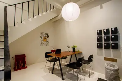 a dining room with a table and chairs and a staircase at Dear Sunday Hometel Bangkok in Bangkok