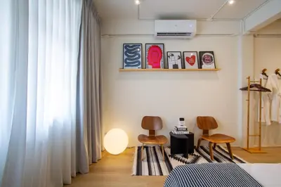 a bedroom with white curtains and two chairs at Dear Sunday Hometel Bangkok in Bangkok
