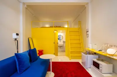 a living room with a blue couch and a yellow room at Dear Sunday Hometel Bangkok in Bangkok
