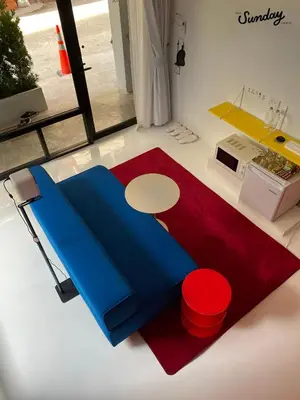 a room with a bed and a table and a red rug at Dear Sunday Hometel Bangkok in Bangkok