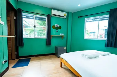a green room with a bed and two windows at GO INN The Giant Swing เสาชิงช้า in Bangkok