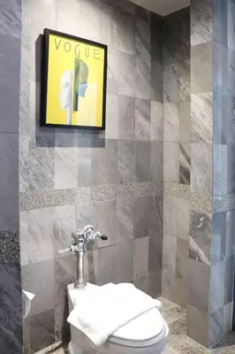a bathroom with a toilet and a poster on the wall at The Quarter Saphankhwai by UHG in Bangkok