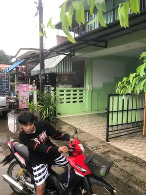 a man sitting on a motorcycle in front of a building at ประเทศไทย in Ban Bang Krang