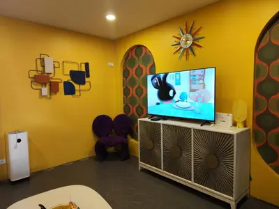 a living room with a tv and a yellow wall at Retrovibes Sathorn BTS ICONSIAM Asiatique Chao Phraya in Bangkok