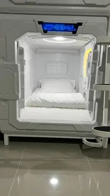 a white bed in the back of a room at Kiwi Capsule Hotel in Bangkok