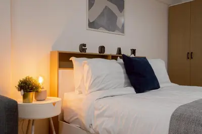 a bedroom with a bed and a table with a lamp at Cosy Lodge MRT Phra Ram 9 in Bangkok