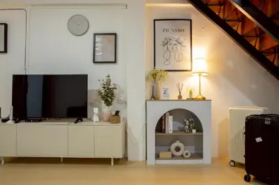 a living room with a television on a white cabinet at Cosy Lodge MRT Phra Ram 9 in Bangkok