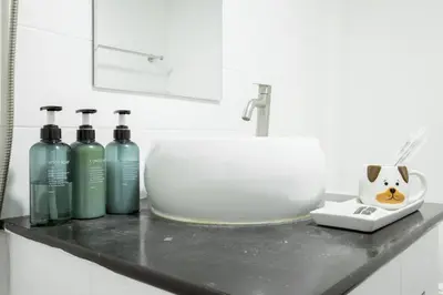 a bathroom counter with a sink and four bottles at Cosy Lodge MRT Phra Ram 9 in Bangkok