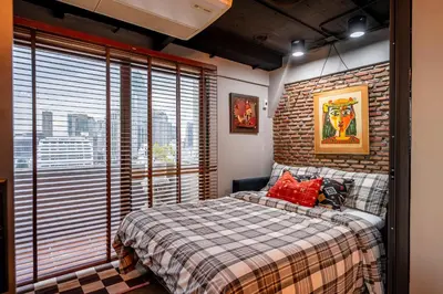 a bedroom with a bed and a brick wall at PEONY Rustic Apartment Sukhumvit, Nana BTS in Bangkok