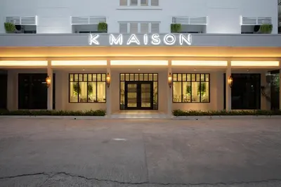 a white building with a sign that reads kuminati at K Maison Boutique Hotel in Bangkok