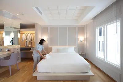a woman standing next to a bed in a room at K Maison Boutique Hotel in Bangkok