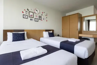 a hotel room with two beds and a clock on the wall at Nature Boutique Hotel Ratchayothin in Bangkok