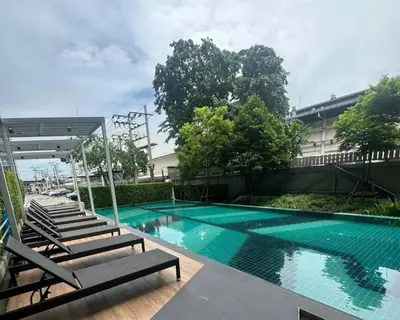 a swimming pool with lounge chairs next to a building at A family room at Lumpini Ville Sukhumvit 101-1 by Pikul in Bangkok