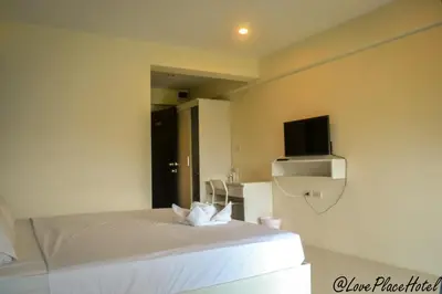 a bedroom with a white bed with a tv on the wall at Sixty Star Love Place Hotel in Bangkok