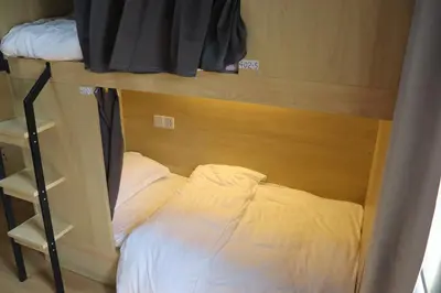 a small bed in a small room with a bunk bed at The Moment Hostel in Bangkok