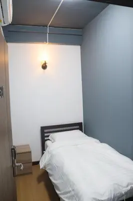 a bedroom with a bed and a light on the wall at The Moment Hostel in Bangkok