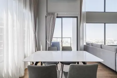 a white table and chairs in a room with windows at loft \u4e8c\u623f\u53ef\u4f4f4\u4eba \u8fd1jodd\u591c\u5e02 \u6e38\u6cf3\u6c60 in Bangkok