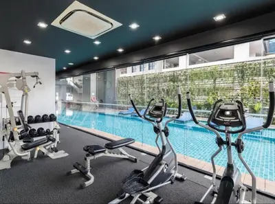 a gym with three exercise bikes and a swimming pool at Mövenpick Residence Ekkamai in Sathani Khlong Tan