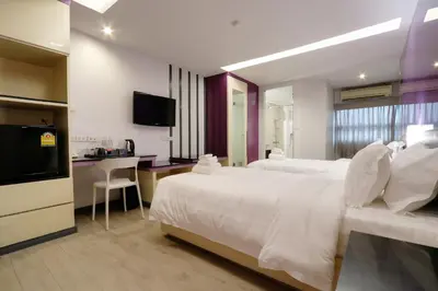 a hotel room with a large white bed and a desk at Klassique Sukhumvit Hotel in Bangkok