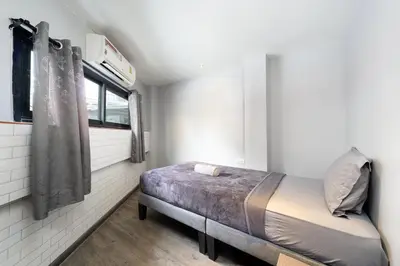 a small bedroom with a bed and a window at OH Hostels - Bangkok in Bangkok