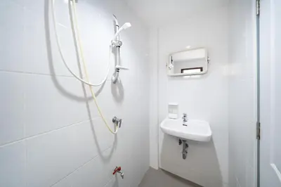 a white bathroom with a shower and a sink at OH Hostels - Bangkok in Bangkok