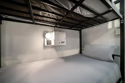 a bunk bed with a clock on the wall at OH Hostels - Bangkok in Bangkok