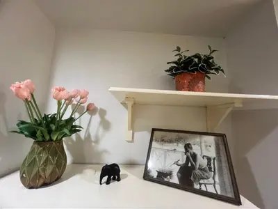 a shelf with a picture and a vase with flowers at Youjia Youth Hostel in Bang Rak