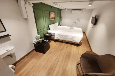 a bedroom with a bed and a chair and a sink at Shade House Bangkok Oldtown in Bangkok