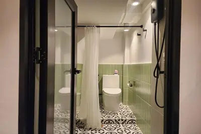 a bathroom with a toilet and a glass shower stall at Shade House Bangkok Oldtown in Bangkok