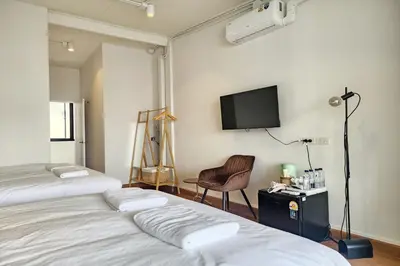 a bedroom with two beds and a tv on the wall at Shade House Bangkok Oldtown in Bangkok